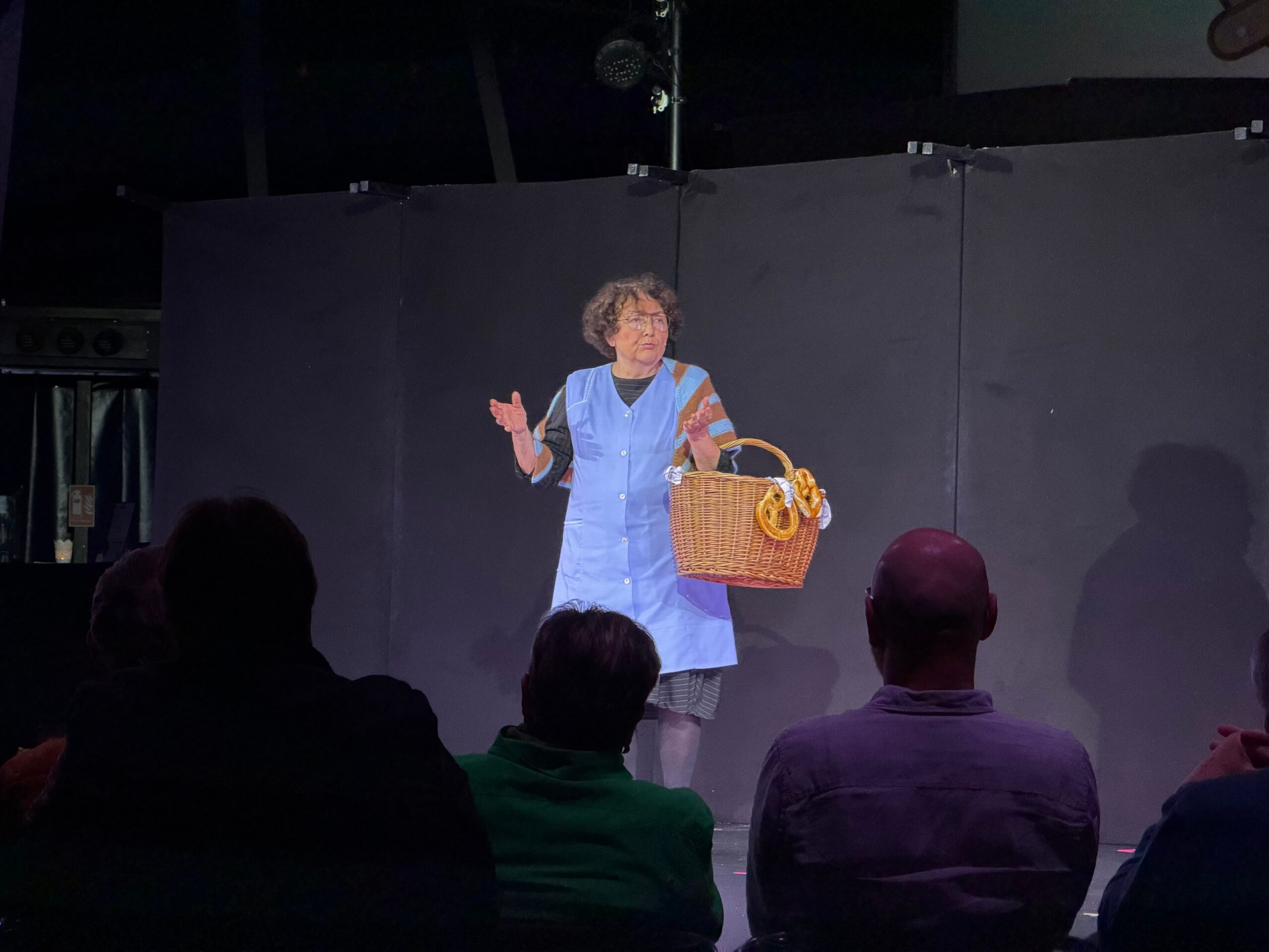 Eine Frau mit blauer Kleidschürze und einem Korb mit Brezeln