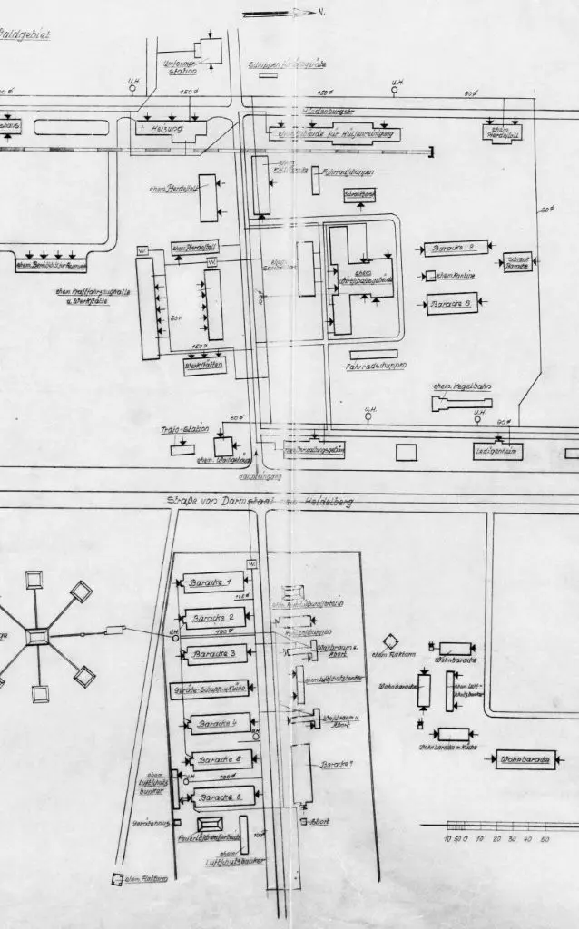 Eine Schwarz-Weiß-Karte zeigt Straßen, Gebäude und mit deutschen Bezeichnungen versehene Kasernen, wobei Häuserblöcke, Straßennamen, Richtungspfeile und verschiedene Gebäudeumrisse in einem übersichtlichen Layout angeordnet sind.