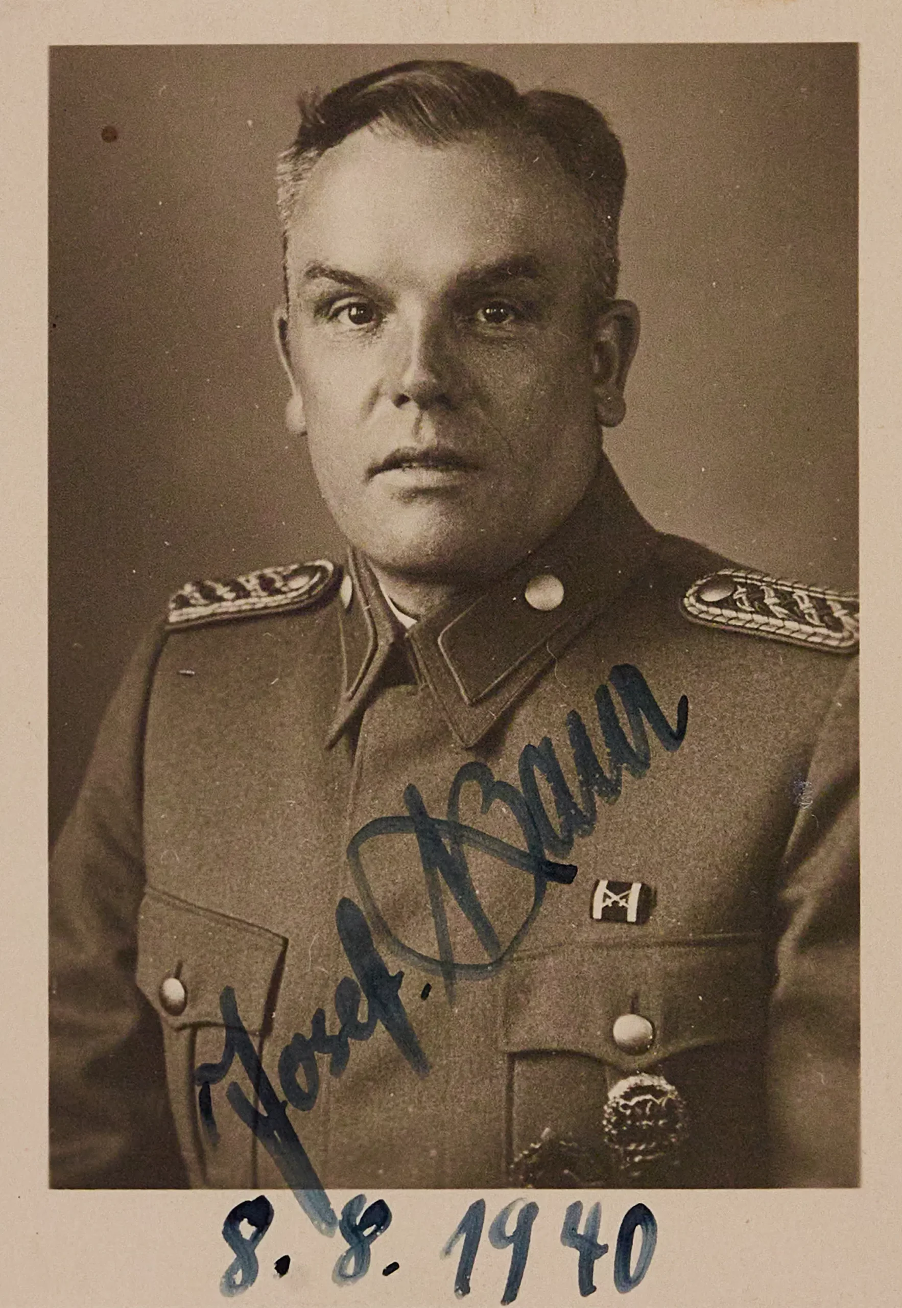 Schwarz-Weiß-Porträt eines Mannes in Militäruniform, der nach vorne blickt. Das Foto ist im unteren Bereich mit einem Namen signiert und mit dunkler Tinte auf den 8.8.1940 datiert.